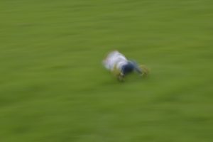 Abstract photograph of child rolling down a hill using a slow shutter speed